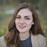 Close-up portrait of a smiling woman with freckles and long hair in a Budapest park during fall.