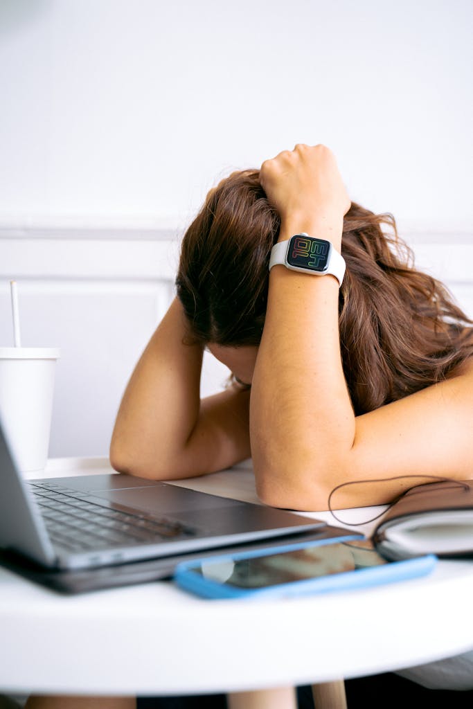 A woman looking overwhelmed at a desk with a laptop, symbolizing remote work stress.